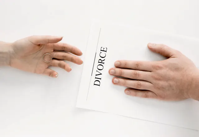 Two hands on either side of a divorce document on a white table